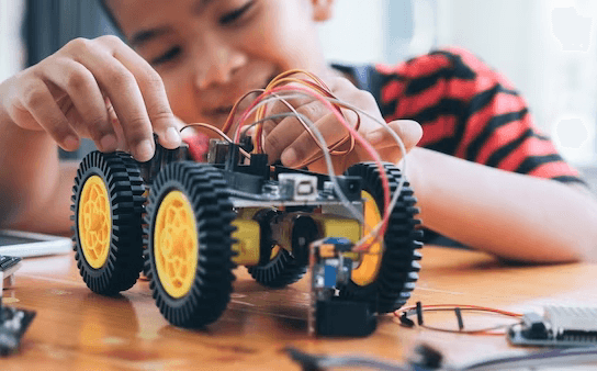 Student building and programming a 4-wheel robotics car with Arduino at STEMmantra lab.